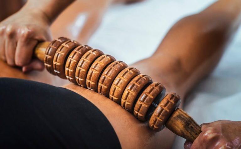 Femme recevant un massage Maderothérapie à Cavaillon Un massage des jambes avec un rouleau en bois pour détendre les muscles.