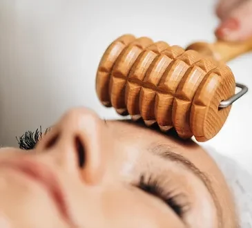 MADEROTHERAPIE VISAGE CAVAILLON Rouleau en bois de madérothérapie visage utilisé pour un massage facial sur une personne détendue.